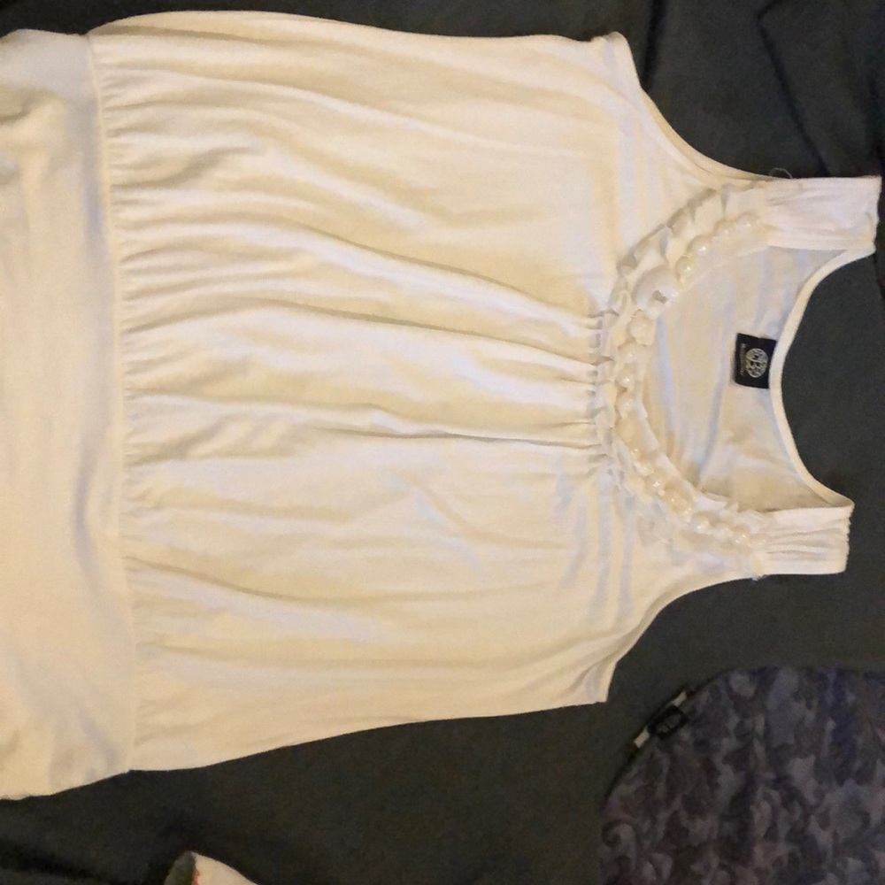 Sleeveless white top, neck lined in pearl